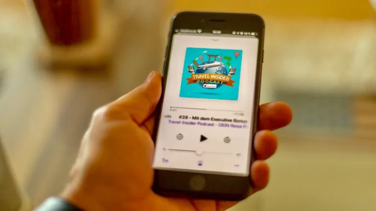 Smartphone in der Hand, auf dem eine Folge des Travel-Insider Podcasts abgespielt wird